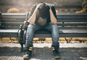 A person sitting with their head in their hands, representing symptoms of depression.