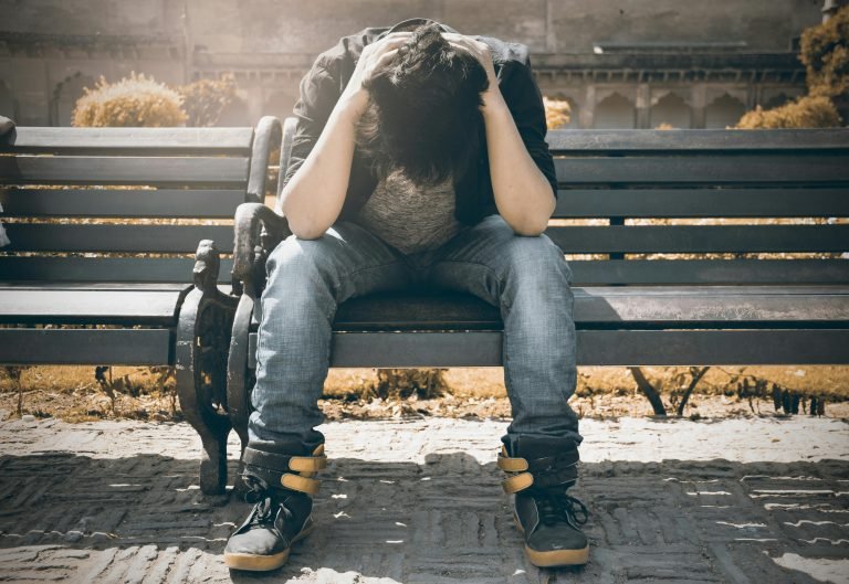 A person sitting with their head in their hands, representing symptoms of depression.